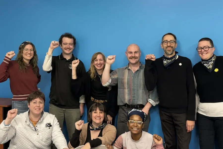 Nine people standing together in solidarity with their fist in the air