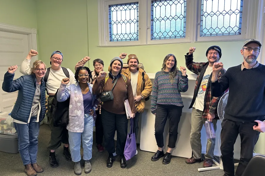 group of 9 people standing together with their fists raised in solidarity