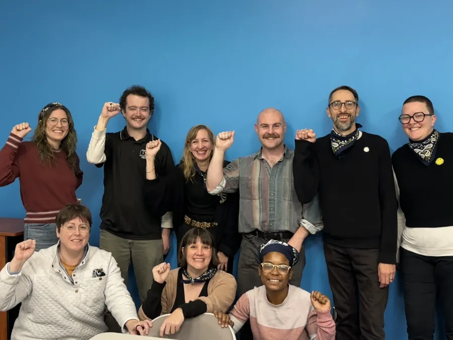 Nine people standing together in solidarity with their fist in the air