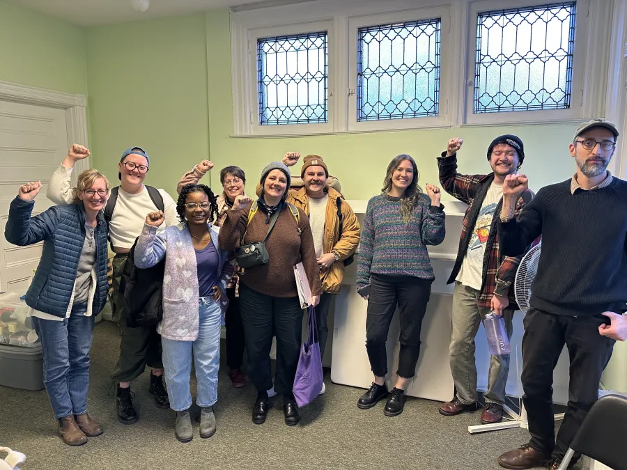 group of 9 people standing together with their fists raised in solidarity